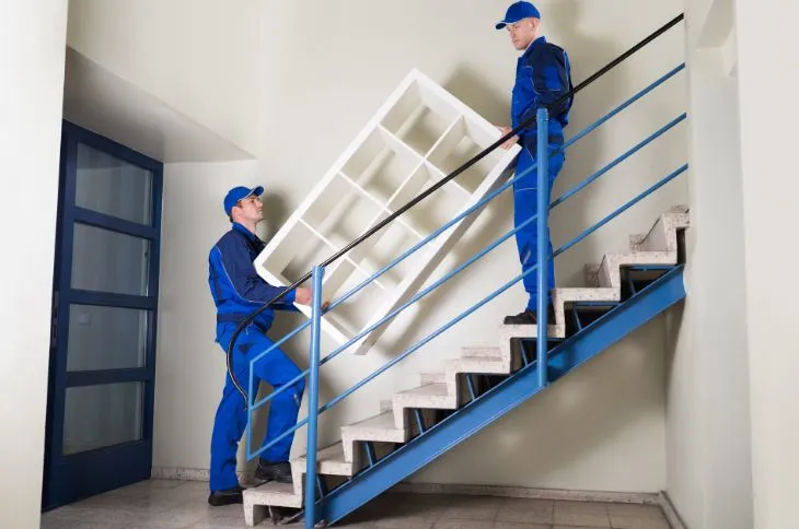 Removal team carry sideboard over stairs